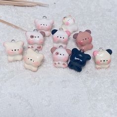 a group of small ceramic bears sitting on top of a white blanket next to knitting needles