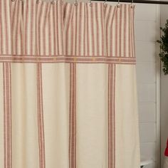 a white toilet sitting next to a red and white shower curtain on top of a bath tub