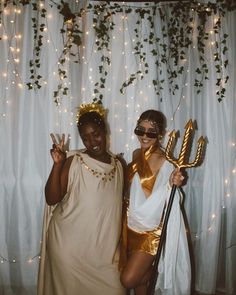 two women dressed up in costumes posing for a photo with one holding a staff and the other wearing a gold costume