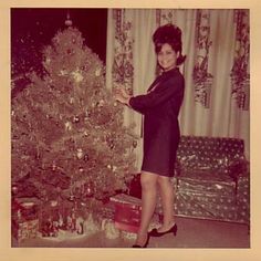 a woman standing in front of a christmas tree