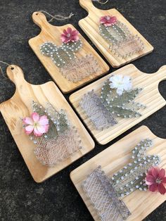 four wooden trays with flowers on them sitting on a black counter top next to some string