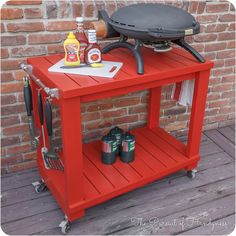 an outdoor bbq table with drinks and condiments on the top, in front of a brick wall