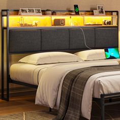 a bed with a laptop sitting on it's headboard next to a night stand