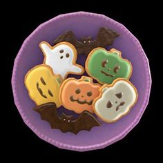 a purple plate topped with halloween cookies on top of a table