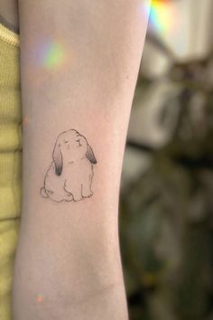 a woman's arm with a small tattoo of a dog on the left side