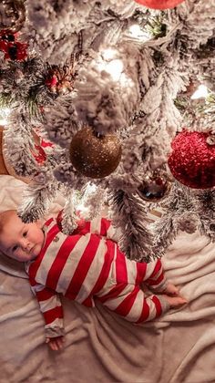 a baby laying in front of a christmas tree