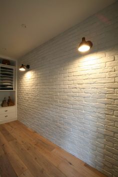 a white brick wall with two lights on it and some shoes in the closet below