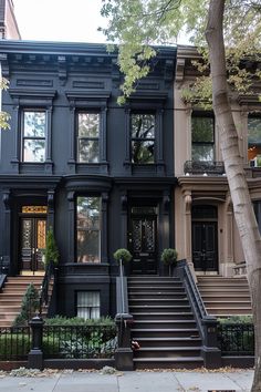 a black house with stairs leading up to the front door and two story building in the background