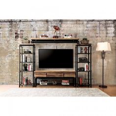 a living room with a large tv on top of a wooden entertainment center in front of a brick wall