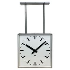 a square clock hanging from a metal frame