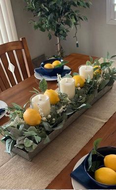 the table is set with candles, lemons and greenery in blue dishes on it