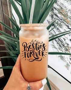 a person holding up a drink in front of a window with the words positive forever on it