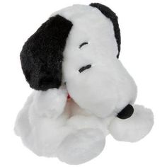 a white stuffed dog with black ears and nose sitting on its side, looking up at the camera