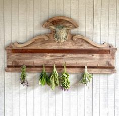 an old wooden coat rack with herbs hanging from it's hooks on the wall