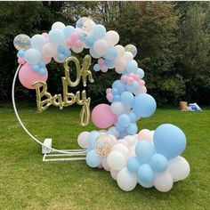 a bunch of balloons that are sitting in the grass with an oh baby sign on it