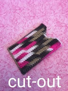 a crocheted cell phone case sitting on top of a pink tablecloth with the words cut - out written across it