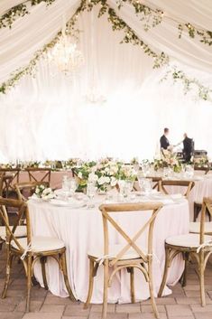 the tables are set up with white linens and greenery for an elegant wedding reception