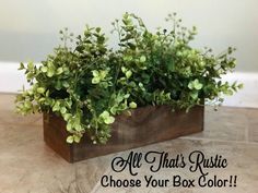 a wooden box filled with green plants on top of a table