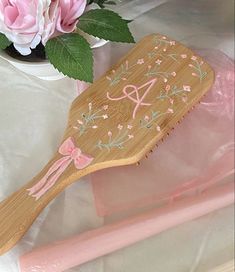 a wooden brush with pink flowers in a vase on a white table cloth next to it