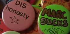 some buttons that say dis honesty, marc sucks and are stacked on top of each other