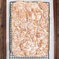 a square cake with white icing on a cooling rack