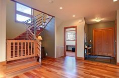 an empty living room with wood floors and stairs