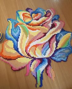 a cross - stitch rose sits on the floor next to a pair of scissors