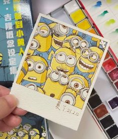 a person holding up a card with some cartoon characters on it and watercolors in the background