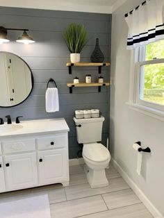 a white toilet sitting in a bathroom next to a sink under a mirror and a window