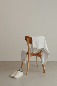 a wooden chair with a white cloth draped over it and a pair of tennis shoes on the floor