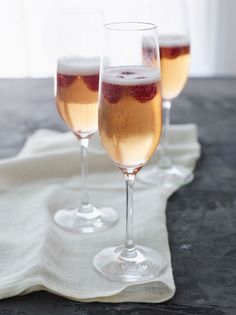 two wine glasses filled with liquid on top of a white cloth next to each other