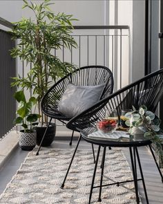 two black chairs sitting on top of a wooden floor next to a potted plant