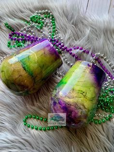 two purple and green glass beads on a white fur