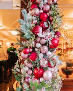 a tall christmas tree with ornaments and greenery on it's sides in a store