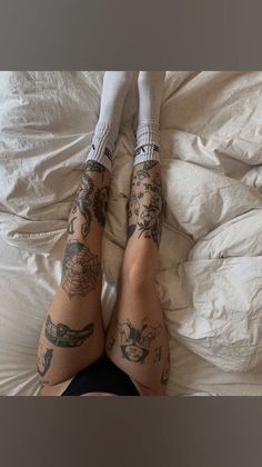 a person laying in bed with tattoos on their legs