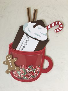 a cup filled with candy canes and marshmallows next to a cookie