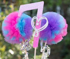 there are two cake toppers on sticks with pink and blue pom poms