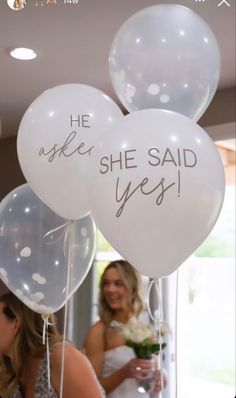 two brides holding balloons with the words he ask she said yes