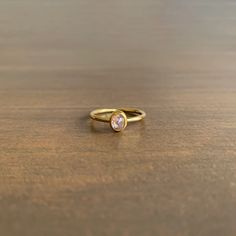 a close up of a gold ring on a wooden table with a white diamond in the center