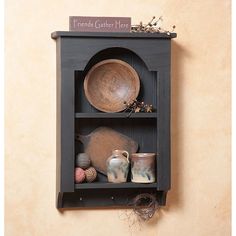 a wooden shelf with bowls and other items on it against a wall mounted plaque that says friends gather here