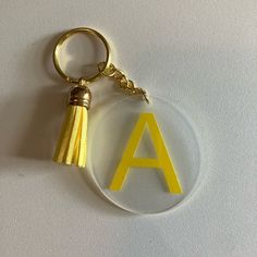 an acrylic keychain with the letter a on it and a tassel