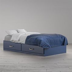 a blue bed with two drawers on each side and a white wall in the background