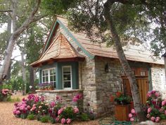 a small stone house with flowers in the front yard