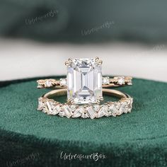 an emerald colored diamond engagement ring set on top of a green velvet cushioned box