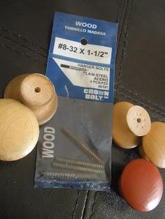 wood turned knobs and screws in package on black leather surface with tags attached to them