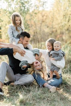 a group of people sitting on the ground with one woman holding a baby and two children