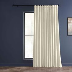 a white curtain hanging in front of a window with blue walls and wooden floors,