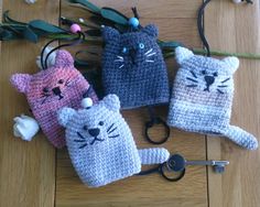 three crocheted cat key fobs are on the floor next to flowers