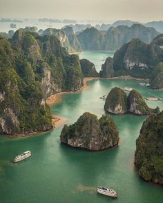 an aerial view of several boats in the water surrounded by green hills and islands with trees on either side