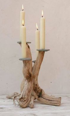 three candles are placed on top of a driftwood tree stump with two smaller ones in the center